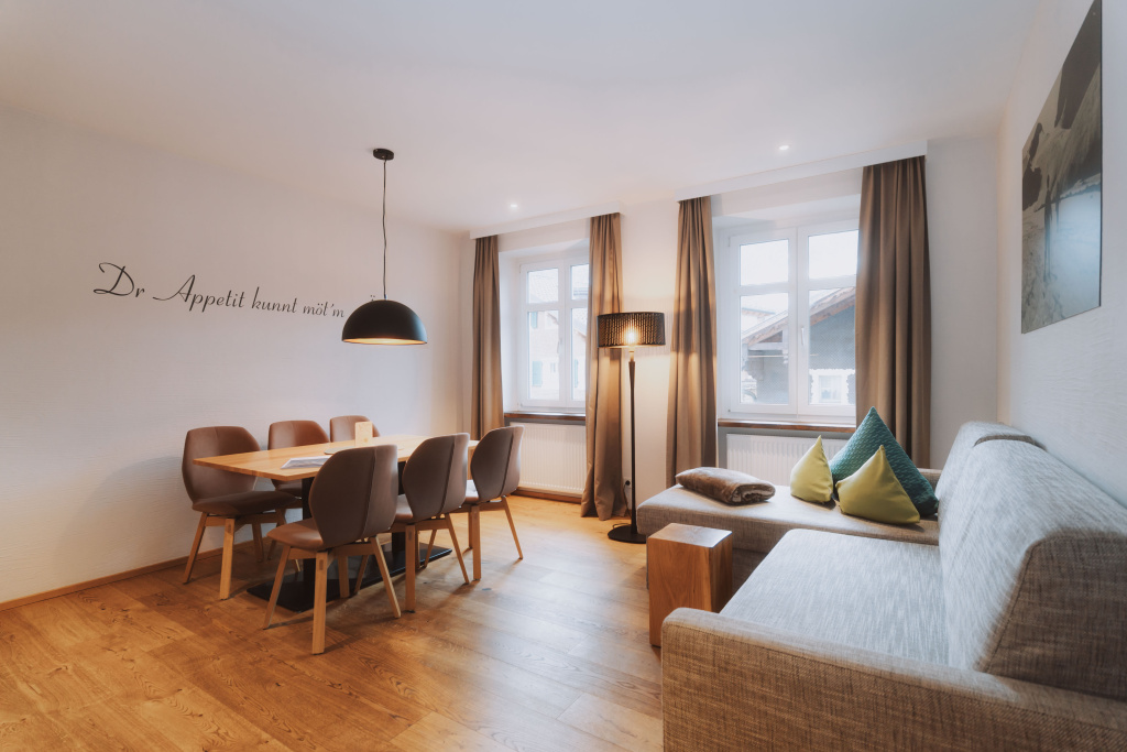 Moderner Wohn- und Essbereich eines Premium-Apartments in Schruns mit Sofa, Esstisch und großen Fenstern