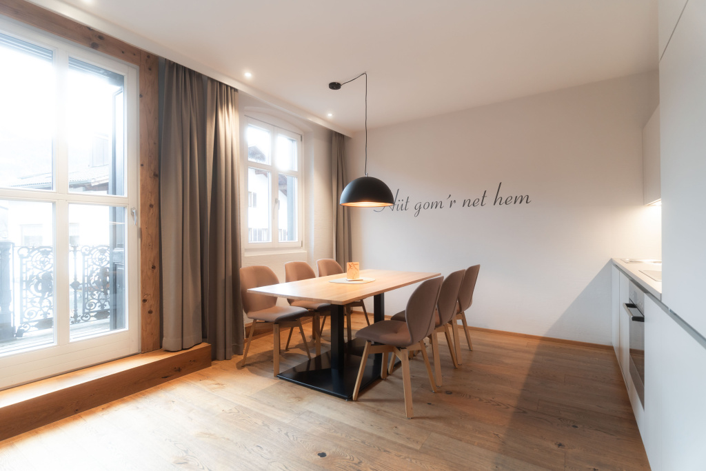 Moderner Essbereich mit Holztisch, sechs Stühlen und offener Küche im Apartment