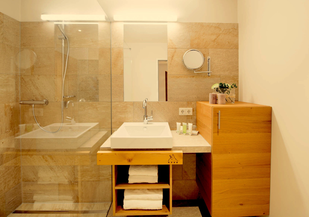 Modernes Badezimmer mit Glasdusche, Waschtisch und Holzschrank in den Adler Alpen Apartments